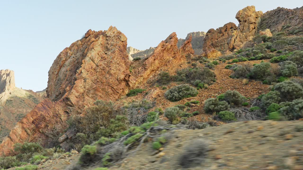 conduciendo a lo largo de las montañas rocosas en el parque nacional del teide en tenerife durante la puesta de sol, paralaje de ángulo bajo de primer plano