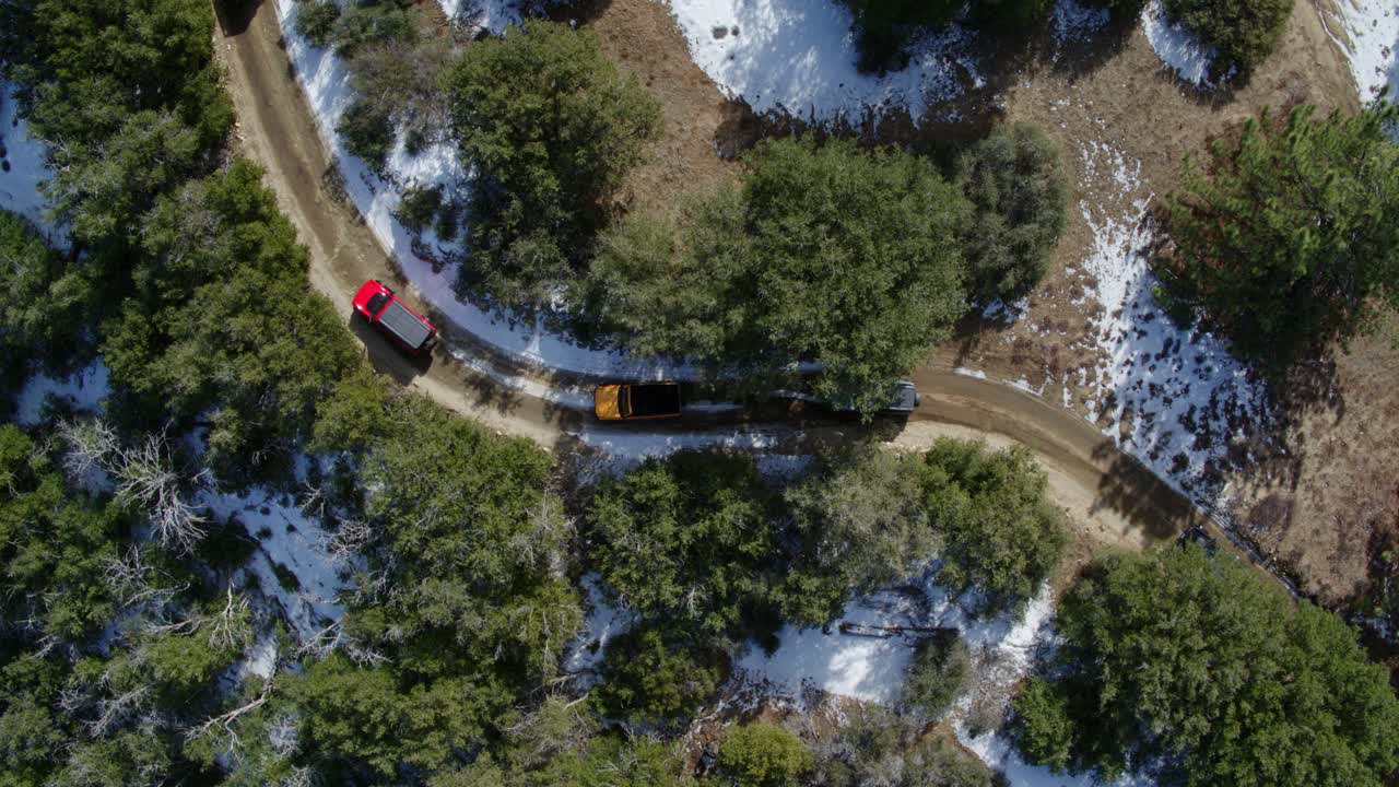 Wide top down aerial shot of weekenders doing a trail ride with their 4x4 SUVs in the mountains.