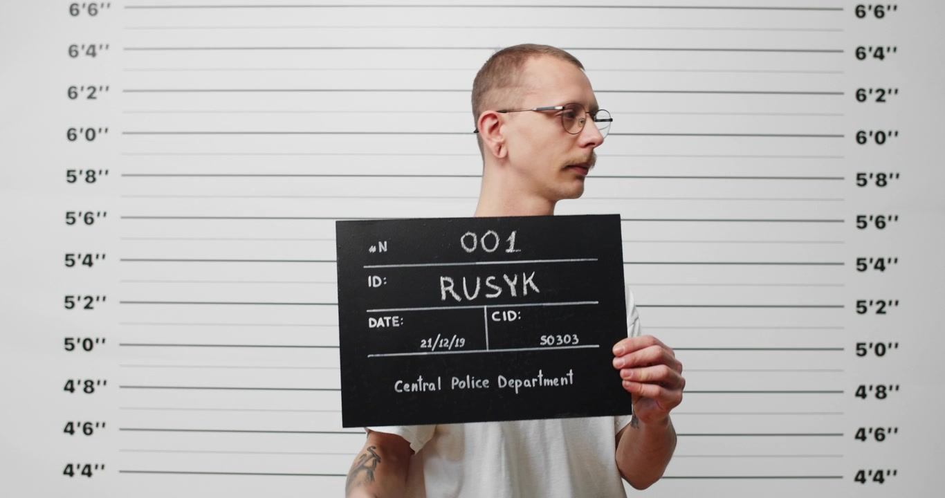 Mladý muž pózující pro policejní fotografii s identifikační tabulkou