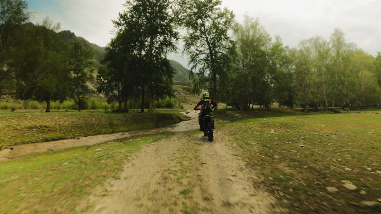 el motociclista atraviesa el arroyo en una carrera de fpv. un motociclista valiente en una motocicleta camina por una ruta fuera de carretera en la naturaleza virgen. las gotas de barro en la cámara