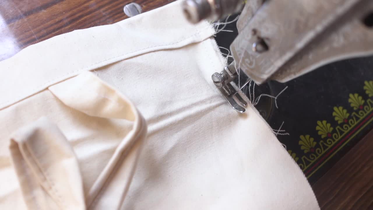 la mano de una mujer rural india no reconocida cosiendo tela en una máquina de coser, primer plano