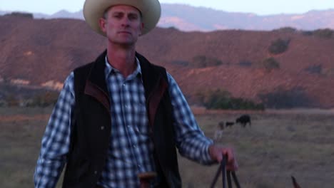 Cowboy-on-his-horse-walks-towards-the-camera-in-golden-hour