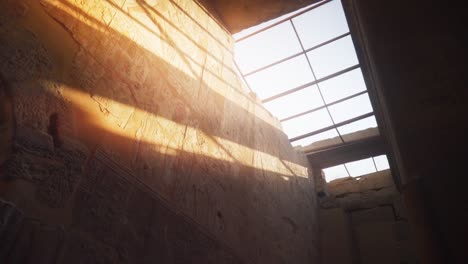 light streaks shining on a wall with hieroglyphs through a roof window inside the kamak temple in luxor, egypt. 
slow camera rotation