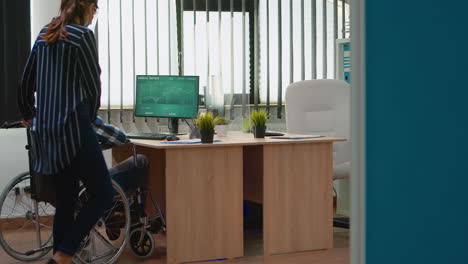 Woman-with-protection-mask-helping-disabled-man-to-get-at-desk