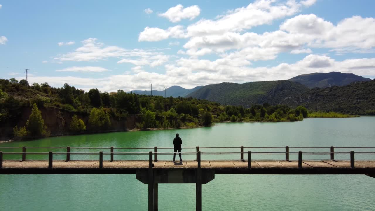 vista aérea de un hombre parado en el puente, sobre el lago verde
