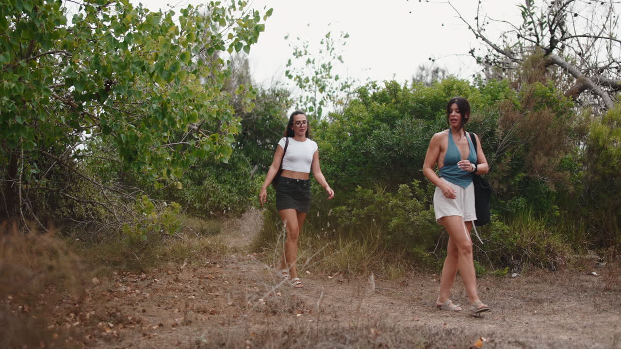 Duas mulheres caminhando em uma trilha ao ar livre no verão