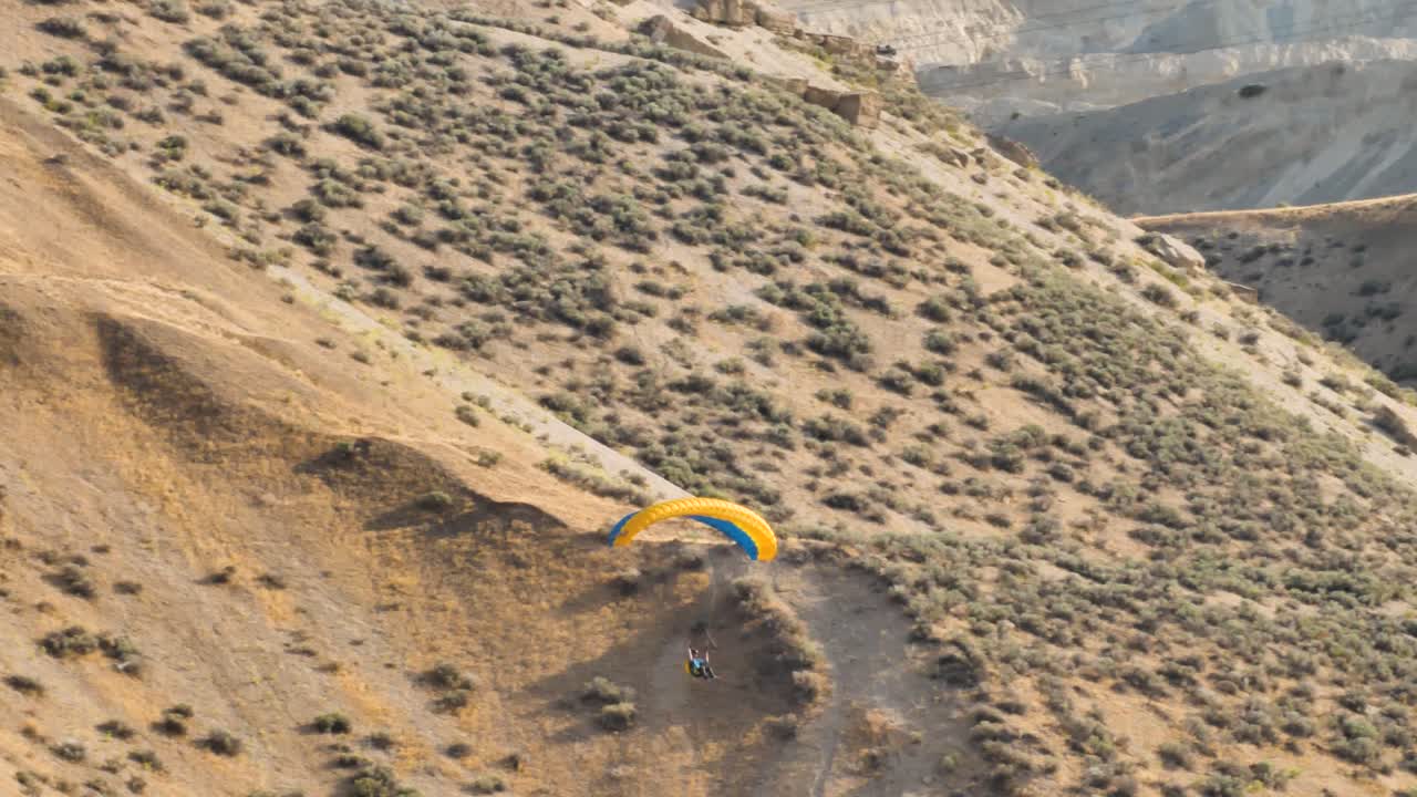 un parapente hace un vuelo elegante por la ladera de una montaña - cámara lenta