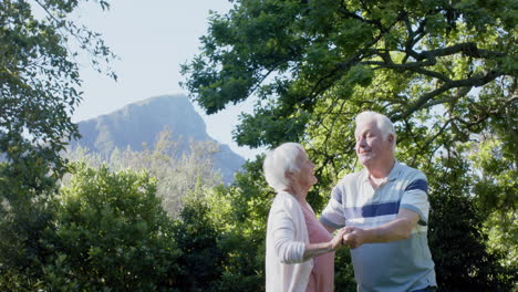 Happy-senior-caucasian-couple-dancing-in-sunny-garden,-slow-motion,-copy-space