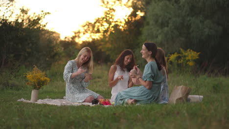 a group of young attractive women in nature in an open area sculpt from clay discuss the results of the lesson communicate share their impressions laugh rejoice at the results. close-up