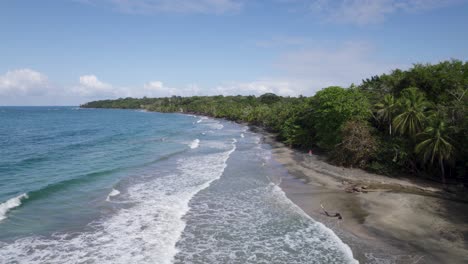 aerial dolly along of manzanillo's scenic coastline and surrounding tropical nature as waves spread white tendrils behind as they crash on shore