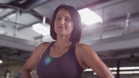 portrait of smiling mature woman wearing fitness clothing standing in gym ready to exercise 1