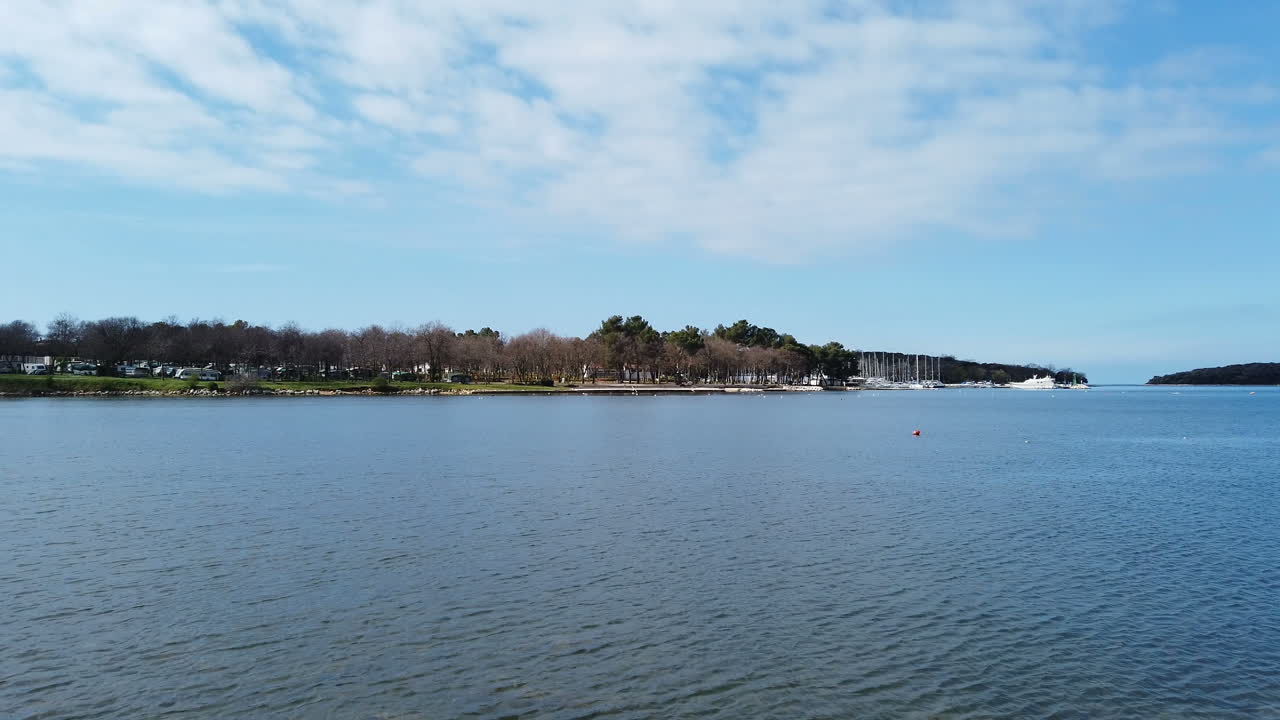 una vista majestuosa del mar bajo un cielo azul claro y una costa rocosa con parches verdes de islas