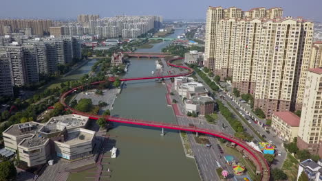 Aerial:-Winding-red-pedestrian-bridge-over-river-canal-in-Suzhou-China