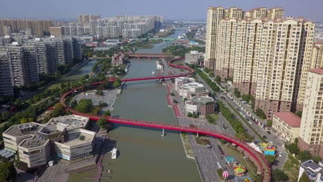 antena: sinuoso puente peatonal rojo sobre el canal del río en suzhou china