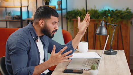 angry furious indian man freelancer using laptop working at home office nervous breakdown at work