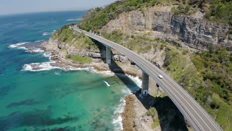 Impresionante-Vista-De-Un-Automóvil-Conduciendo-En-El-Puente-Del-Acantilado-Marino-A-Lo-Largo-De-Grand-Pacific-Drive-Cerca-De-Wollongong-En-Nueva-Gales-Del-Sur,-Australia