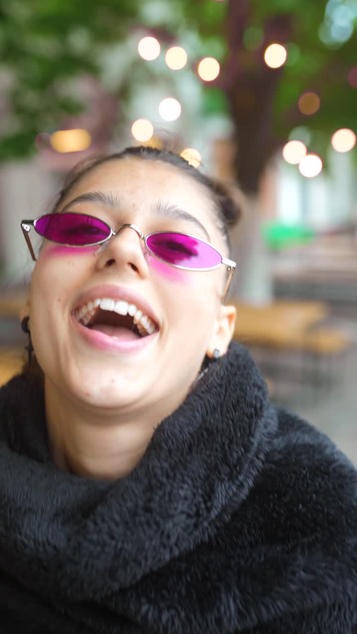 una mujer joven con gafas de sol rosas.