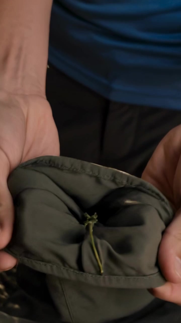 Video verticale: Uomo che cammina in camicia blu, porta un cesto, sistema una giacca su un tavolo da portico con un cavo.