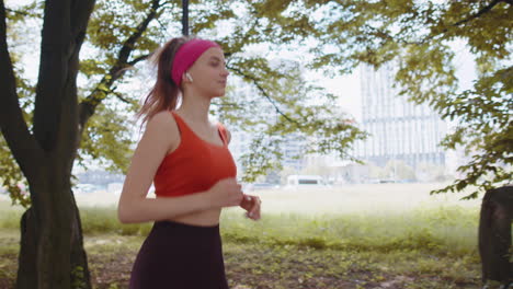 Athletic-fitness-sport-runner-girl-training-marathon-run,-listening-music-in-earphones-in-park