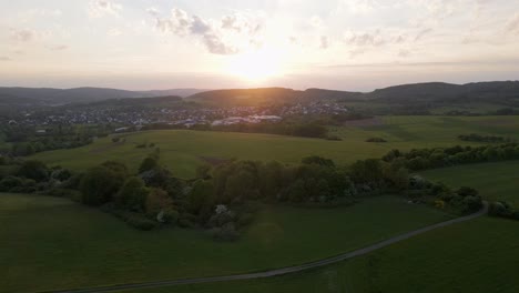 Vista-Aérea-Deslizante-De-Una-Vibrante-Puesta-De-Sol-Sobre-El-Campo-Europeo-Durante-La-Primavera