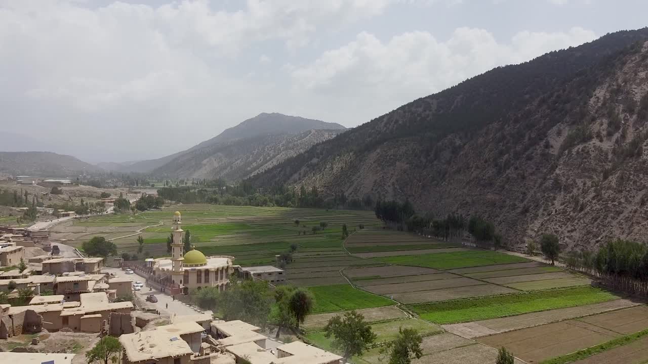 Ripresa aerea con drone dell'incantevole paesaggio rurale di Zazai Aryub Paktia, Afghanistan, con il suo storico villaggio di fango nelle lussureggianti campagne tra le montagne dell'Hindu Kush