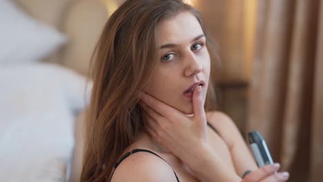 retrato de una chica sexy fumando un cigarrillo de electrones y acariciando su cara