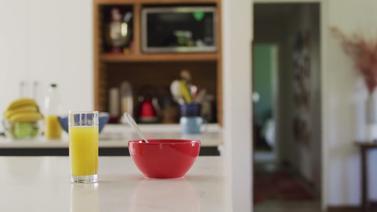 Close up of red bowl and glass of juice on countertop in kitchen