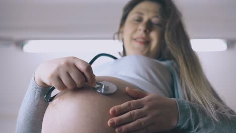 mujer embarazada escucha al bebé con un estetoscopio en el abdomen