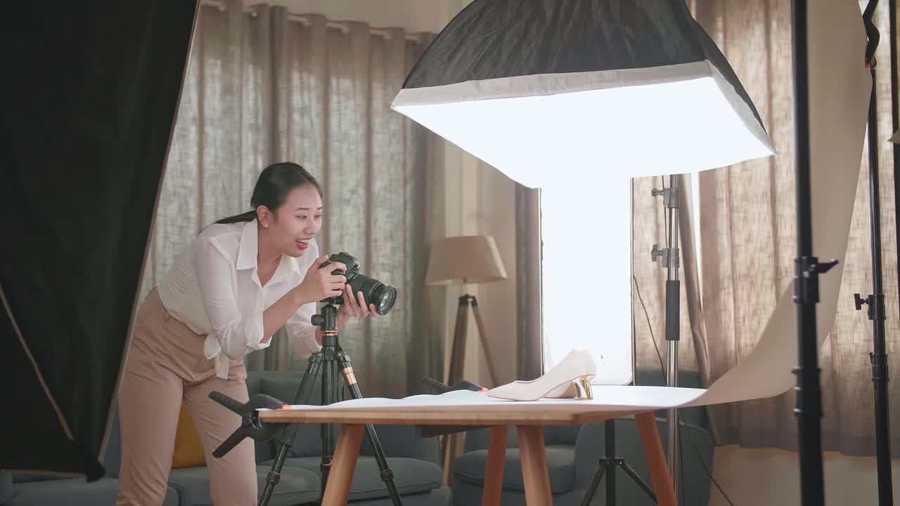아시아 여성 사진작가가 가정 스튜디오에서 여성 신발의 사진을 찍고 있습니다.