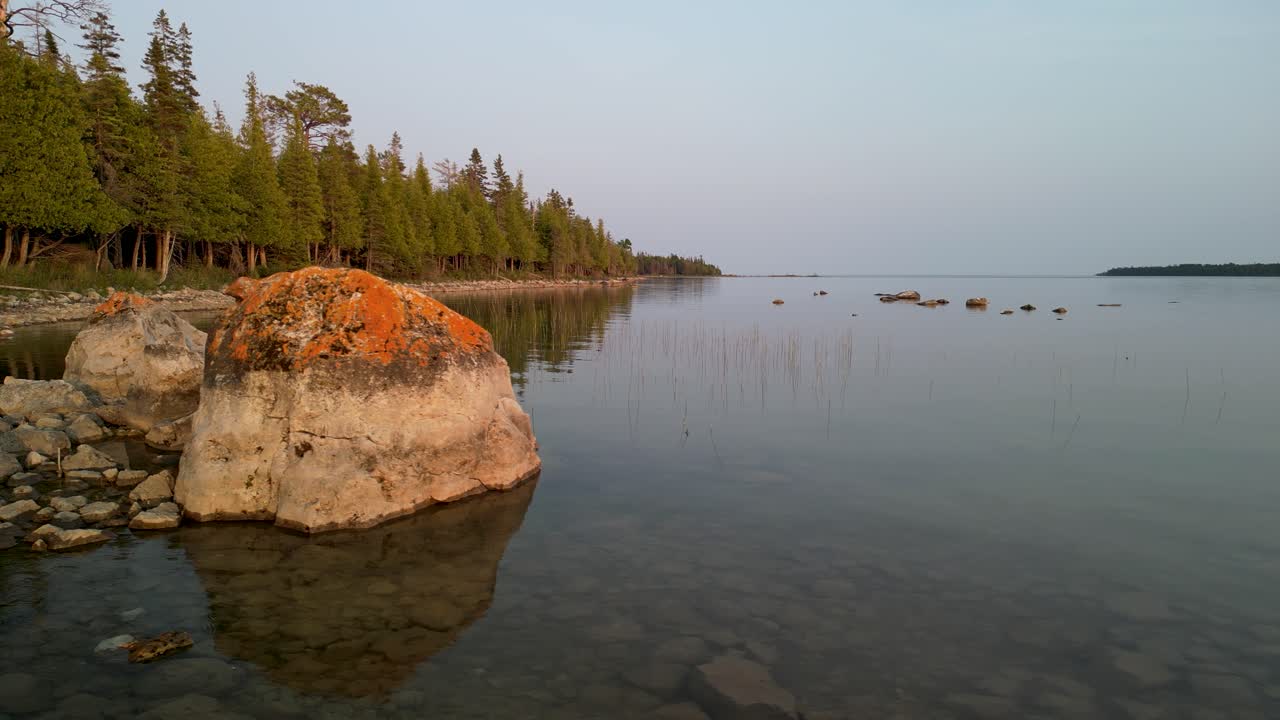 Orbitale Luftaufnahme von großen Felsbrocken entlang der bewaldeten Seeküste in Michigan.