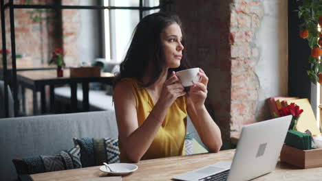 woman working on laptop in a cafe, drinking coffee