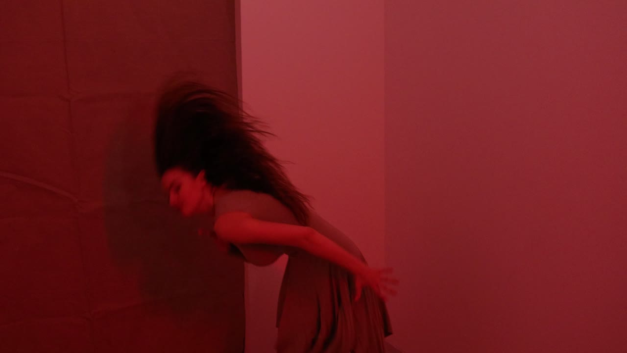 actuación de danza femenina por una bailarina europea en una habitación iluminada de rojo en una oscuridad