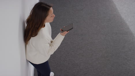 fotografía aérea de una mujer estresada o ansiosa sentada en el suelo apoyada en la pared en casa reaccionando a un mensaje o historia de noticias en internet o redes sociales en el teléfono móvil 2