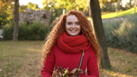 Porträt-Einer-Glücklichen-Frau-Mit-Rotem-Kopf,-Die-Blätter-Herumwirft-Und-An-Einem-Herbsttag-Nach-Oben-Schaut