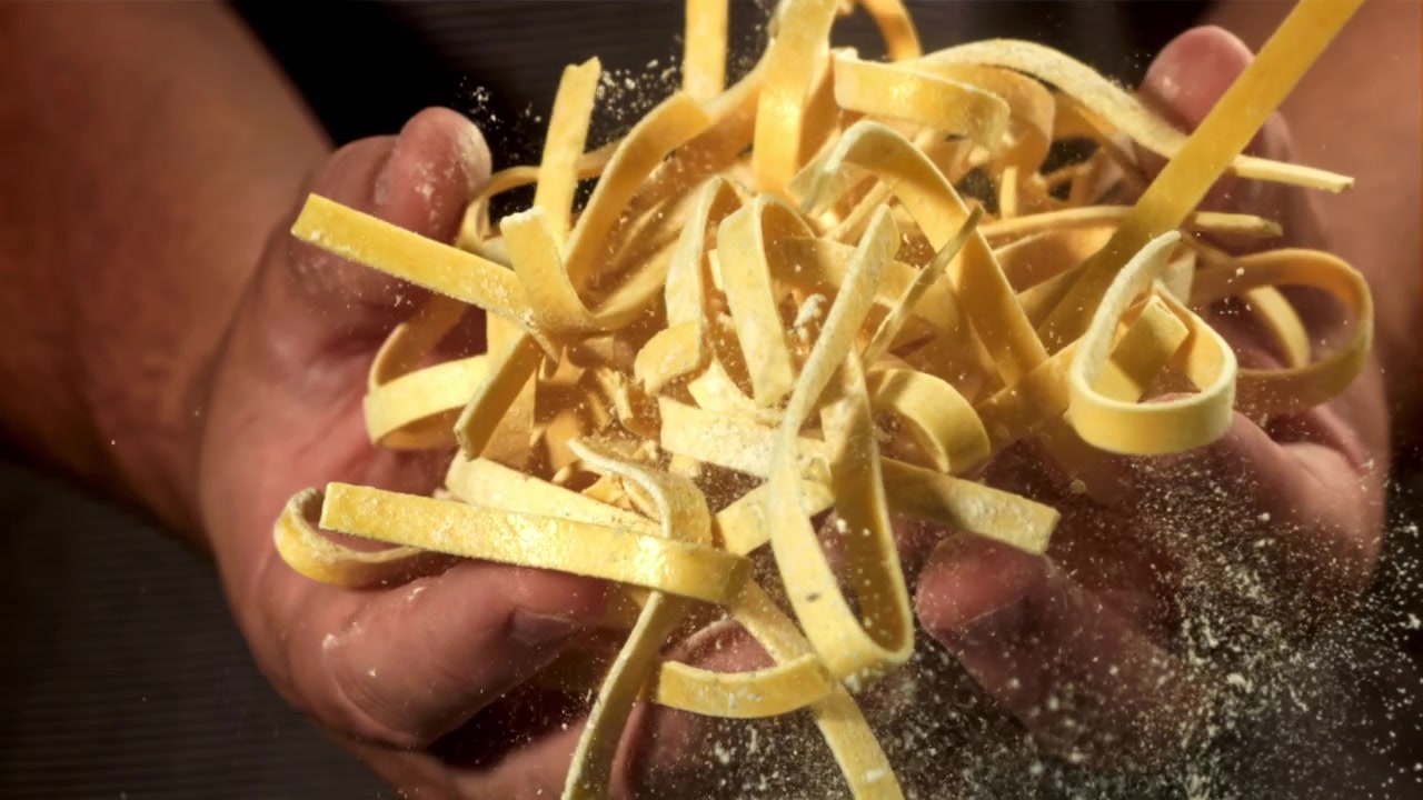 Tagliatelle fresche che cadono nelle mani al rallentatore