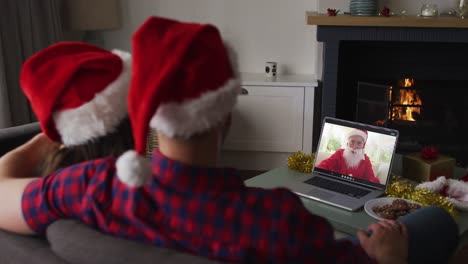 caucasian couple on video call with santa claus at christmas time