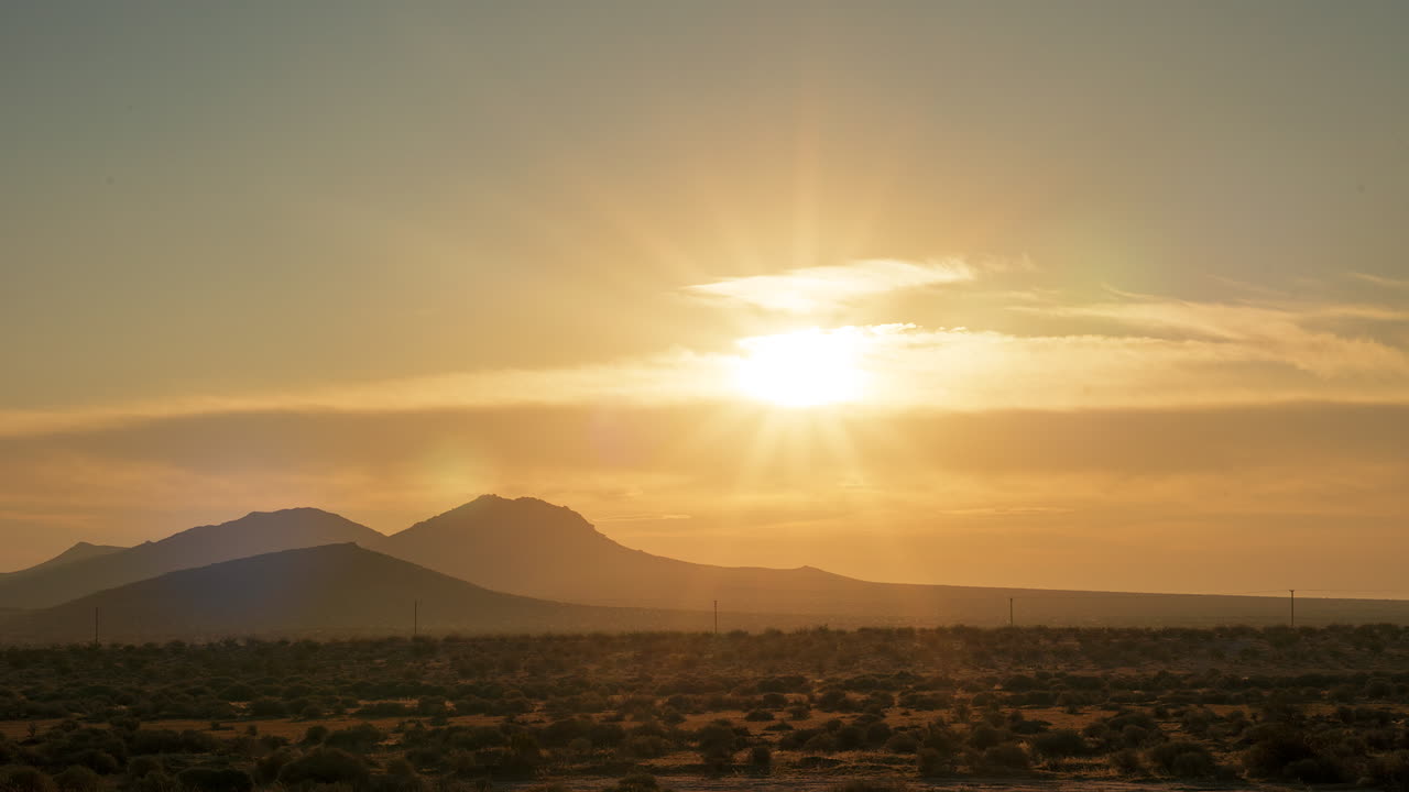 un amanecer dorado se rompe sobre el paisaje árido y duro del desierto de mojave - lapso de tiempo estático
