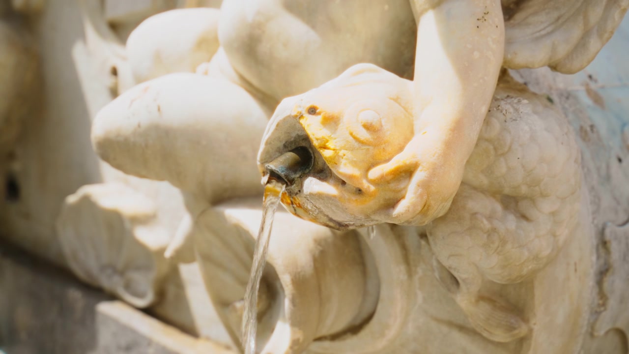 Fontana d'acqua con un pesce di marmo intagliato tenuto da una statua ad Amalfi
