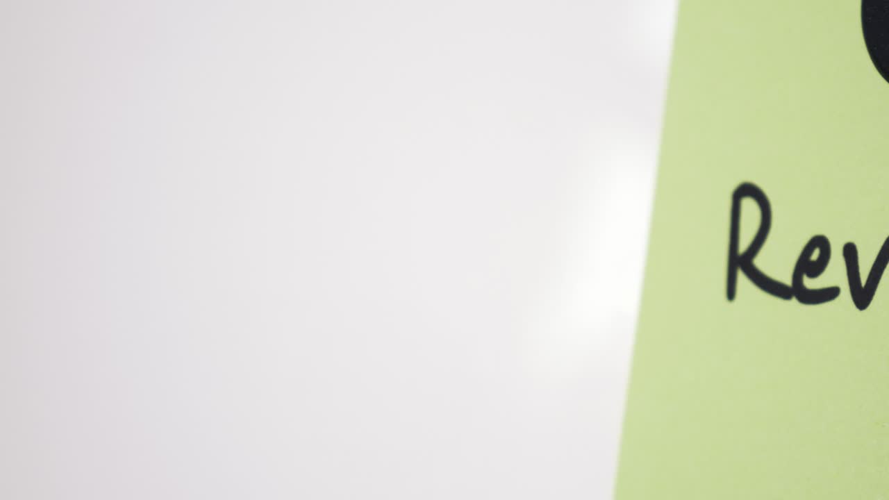 Pan reveal of Revenue text on green note held by magnet on whiteboard with selective focus