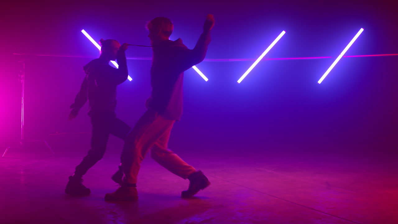 Cool couple dancing playfully in nightclub. Stylish dancers moving body on stage