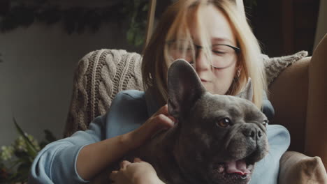 close up view of red haired woman caresses her bulldog dog while they are sitting on the sofa in the living room at home 1