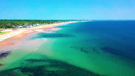 aerial drone view of crowded saco beaches in maine. tourists sunbathe, swim, and play. vacation houses line the busy sand, atlantic ocean waves crash in. peak-season east coast coastal paradise.