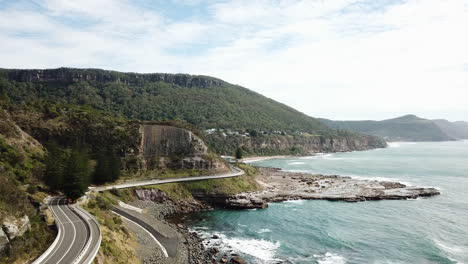 Antena:-Drone-Volando-Junto-A-Una-Carretera-Con-Curvas-Entre-El-Océano-Y-Los-Acantilados,-En-Nueva-Gales-Del-Sur,-Australia