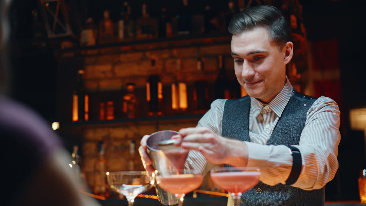 Barman che usa lo shaker per preparare un cocktail in un bar, ripreso da vicino. Barista che prepara da bere