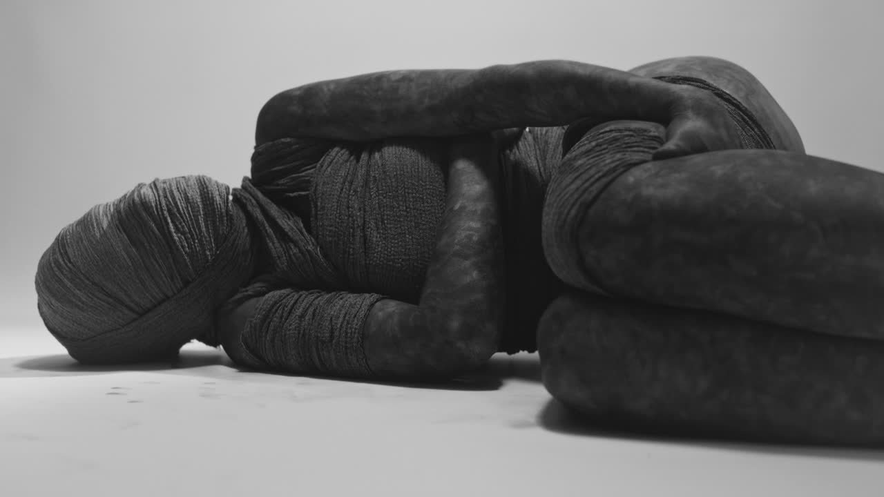 A mummy of a woman lying on the white backdrop
