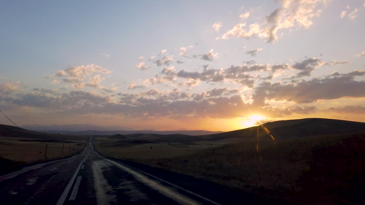 vista desde el interior del coche en una carretera montañosa vacía que conduce a la línea del horizonte al atardecer o al amanecer