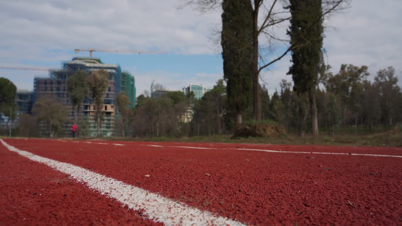 pista de atletismo en el parque con fondo de construcción de la ciudad, actividad deportiva en el barrio suburbano