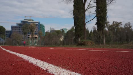 Running-track-on-park-with-city-building-background,-sportive-activity-on-suburban-neighborhood