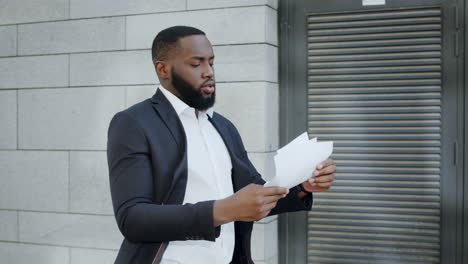 Businessman-looking-at-documents-on-city-street.-Manager-walking-on-street