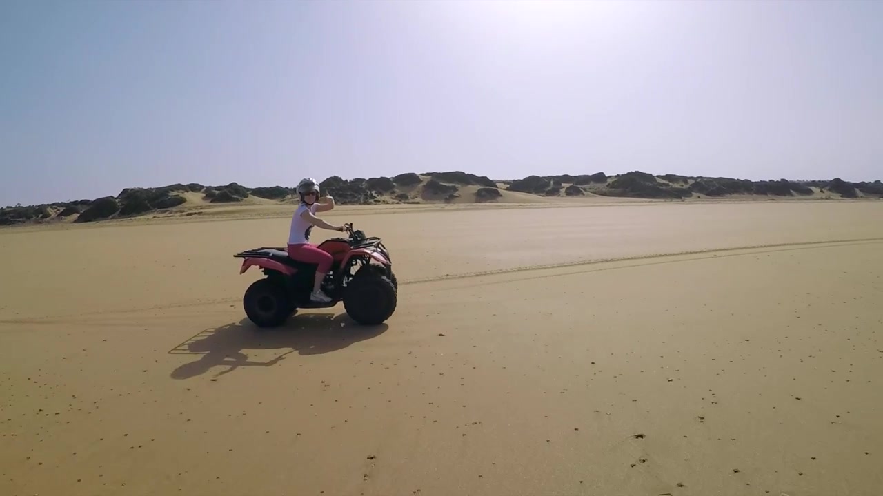 Ragazza che guida velocemente un quad lungo la spiaggia in Marocco